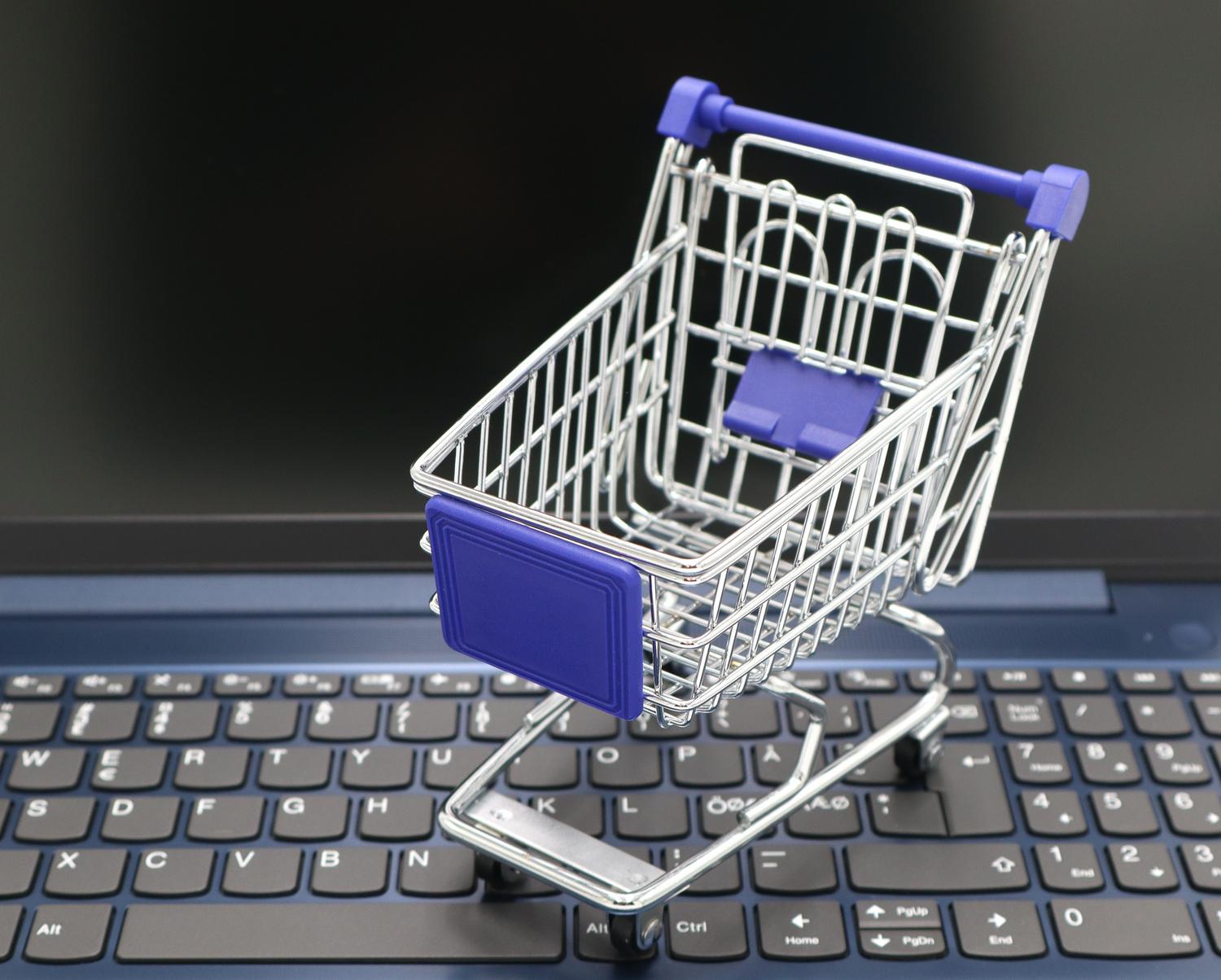 A miniature shopping cart placed on a laptop keyboard, symbolizing the intersection of technology and digital retail for e-commerce scraping.