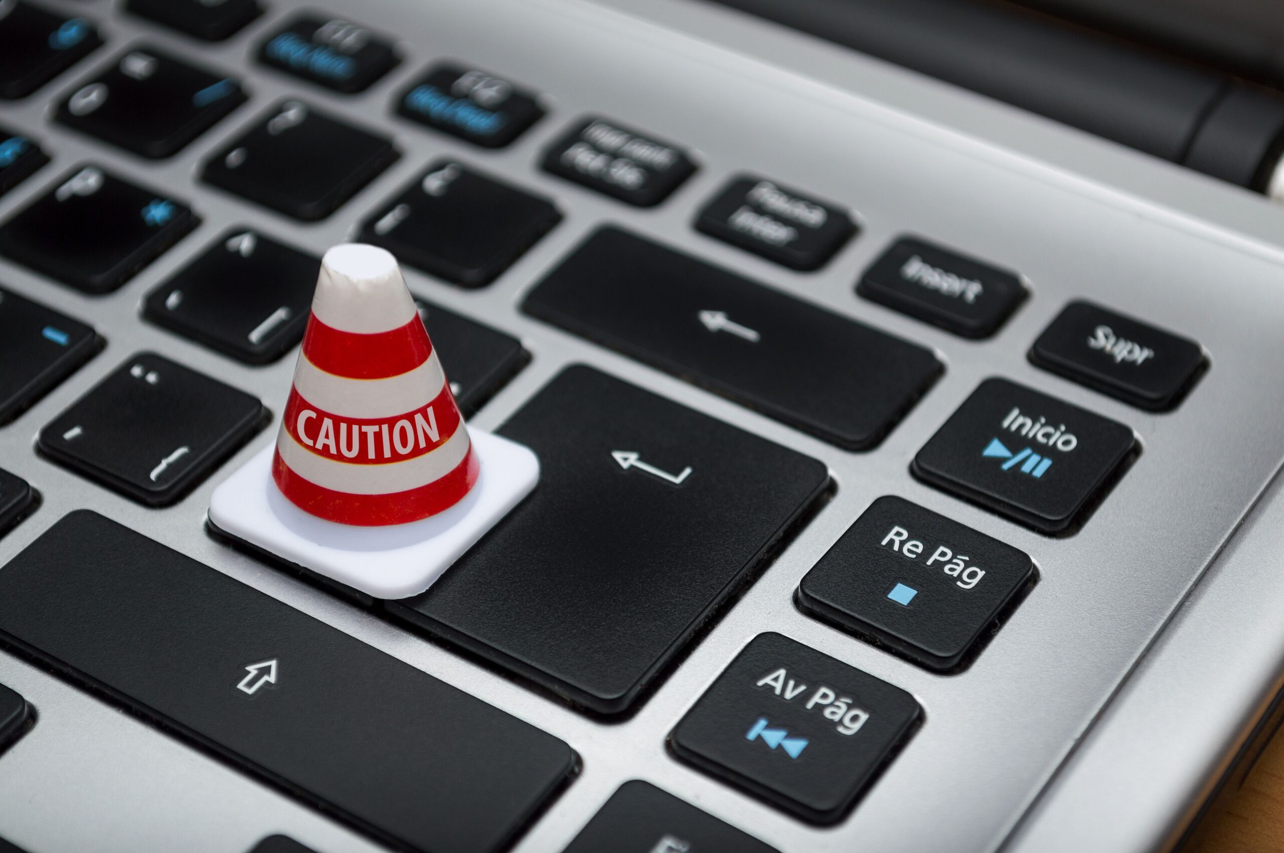 Um pequeno cono de precaução sobre um teclado de computadora, simbolizando a restrição de acesso e o bloqueio de sites web.