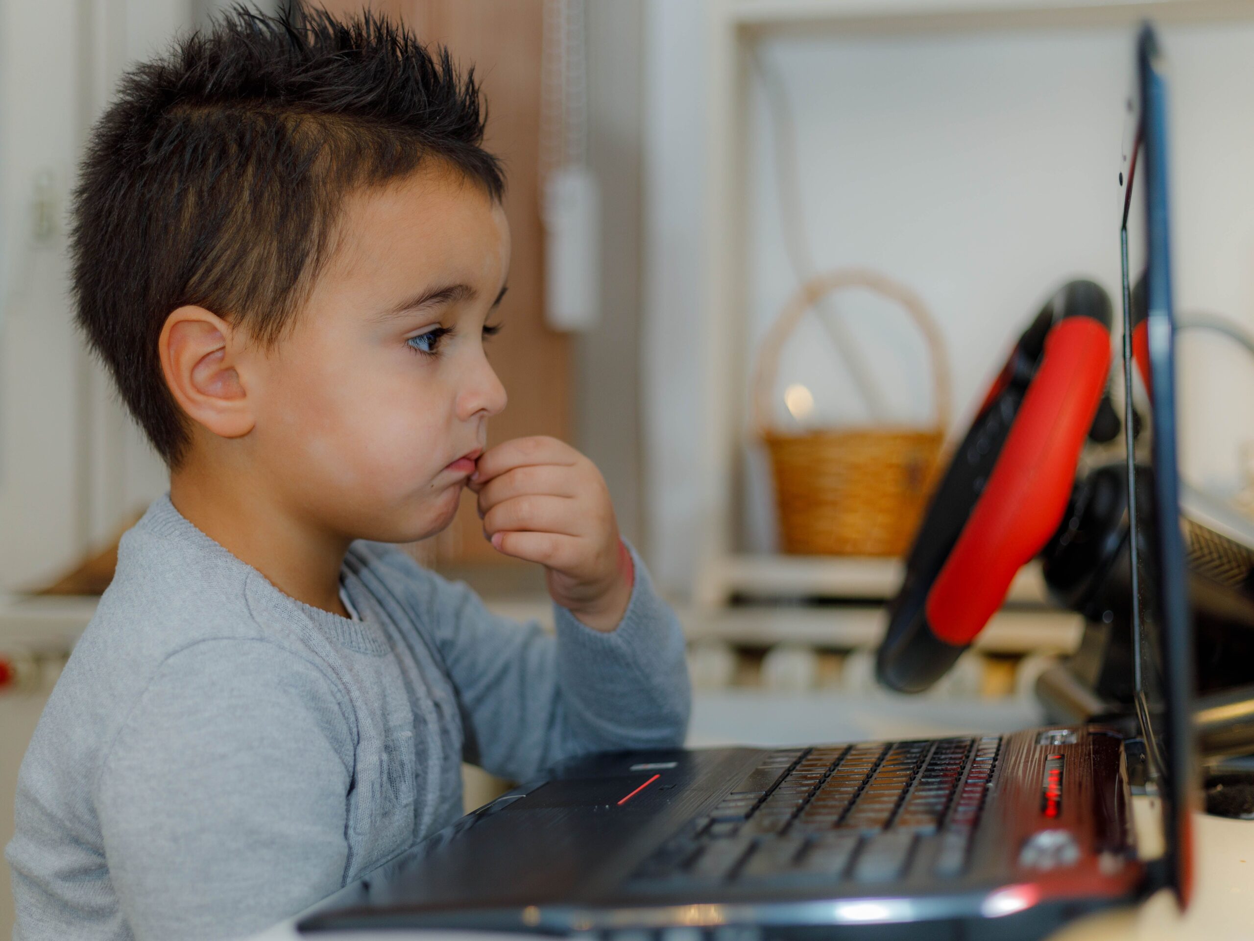 Niño pequeño concentrado usando un portátil, representando la implementación de controles parentales y el filtrado de contenidos para menores.