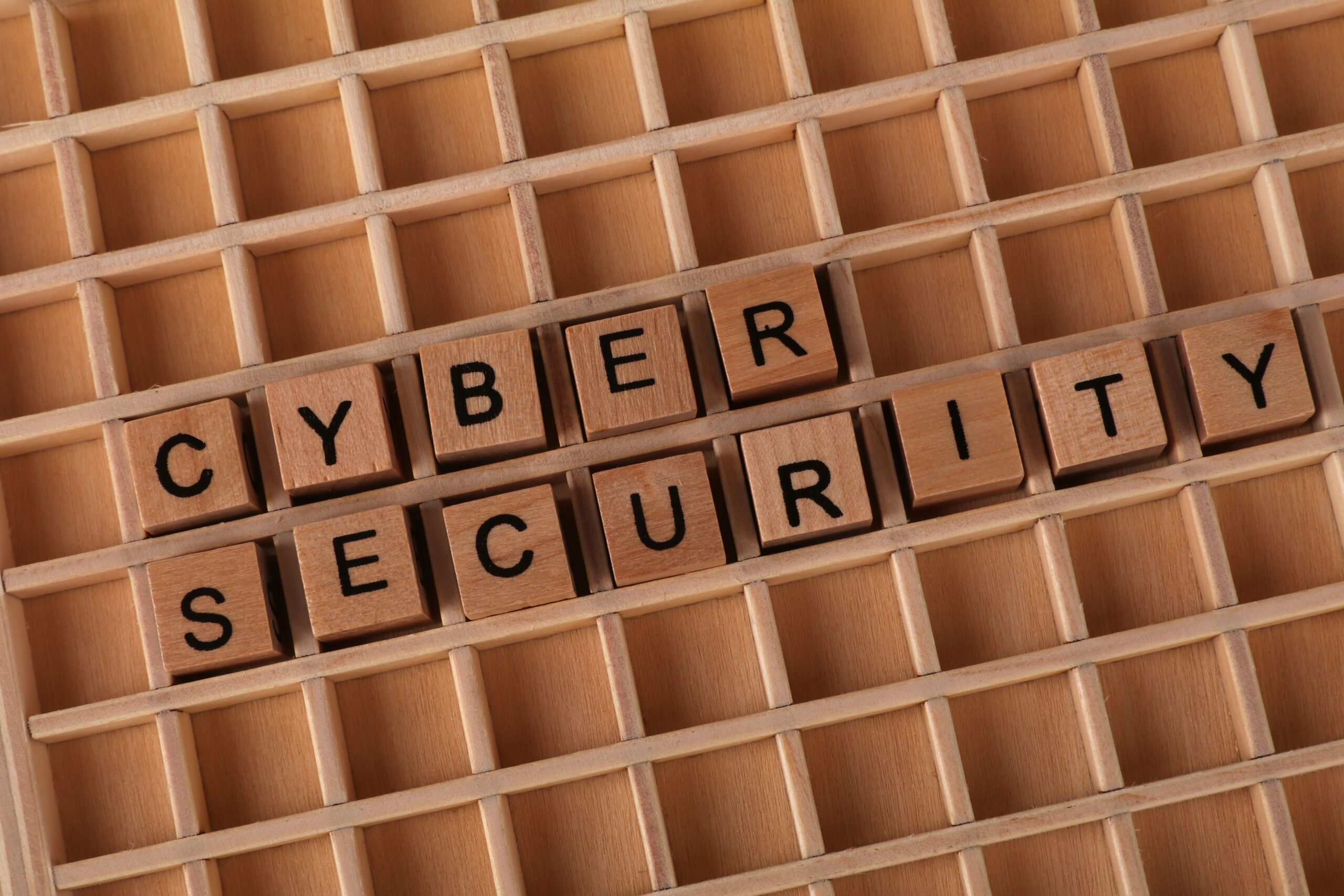 Bloques de madera formando la frase 'Cyber Security' sobre um fundo neutro, representando a base da segurança digital.