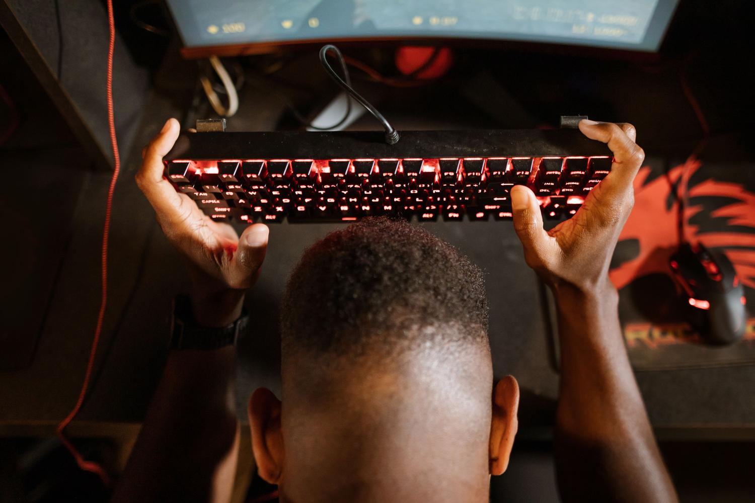 Gamer frustrado sosteniendo el teclado debido a errores de conexión en el juego.