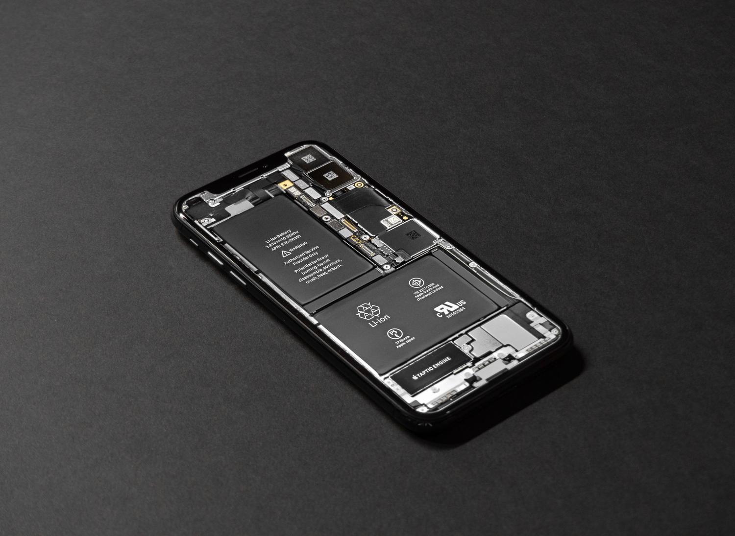 Primer plano de la placa base y circuitos internos de um teléfono móvil sobre um fondo oscuro.