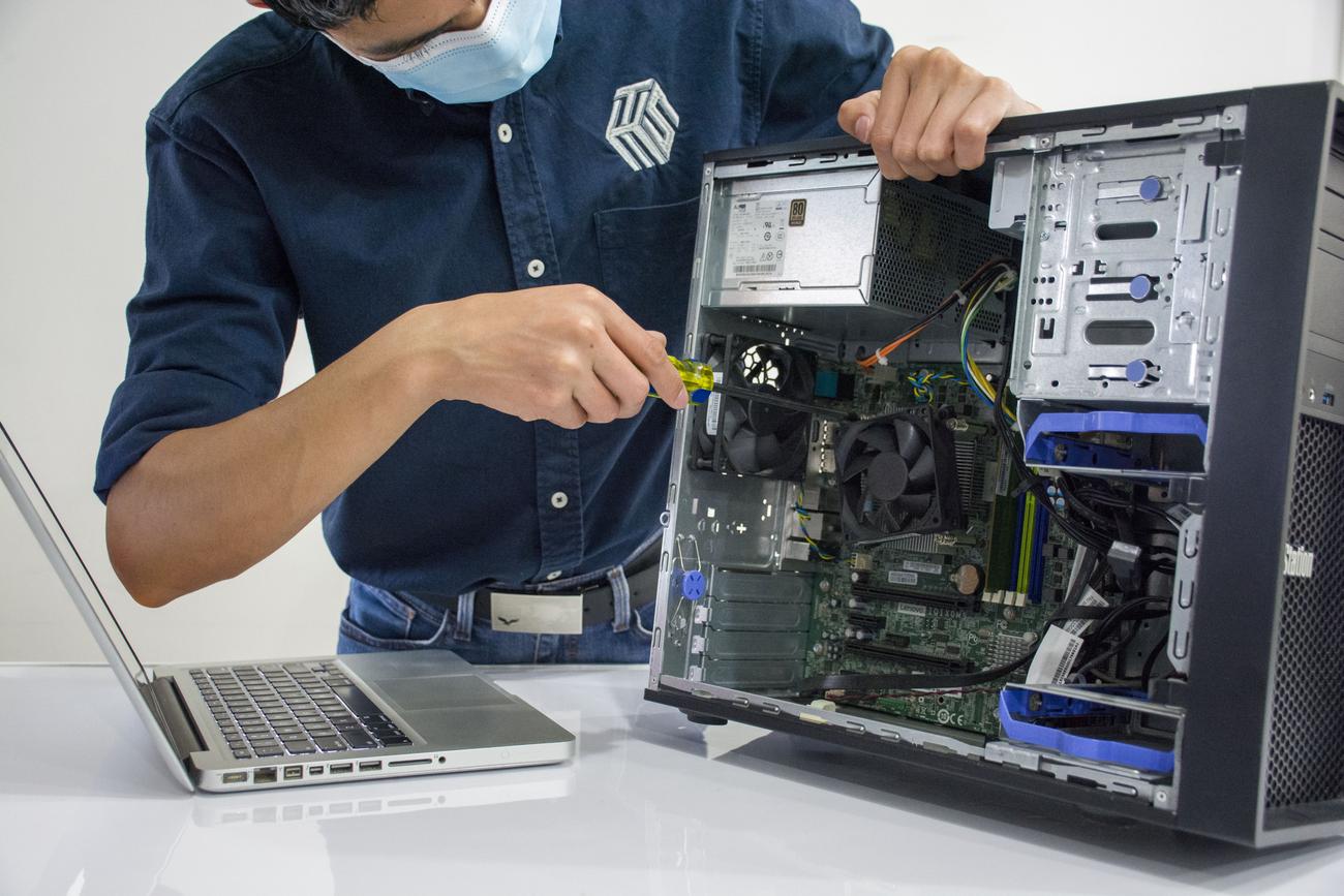 IT technician repairing a desktop computer, symbolizing professional technical assistance for system recovery.
