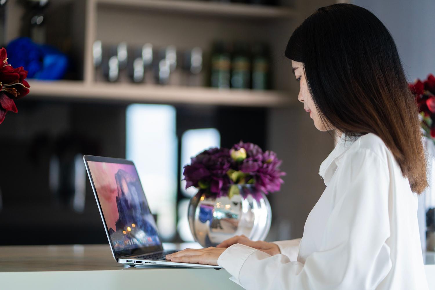 Profesional trabajando con un ordenador portátil en un espacio de trabajo moderno y elegante, ideal para el perfil de ejecutivos y nómadas digitales.