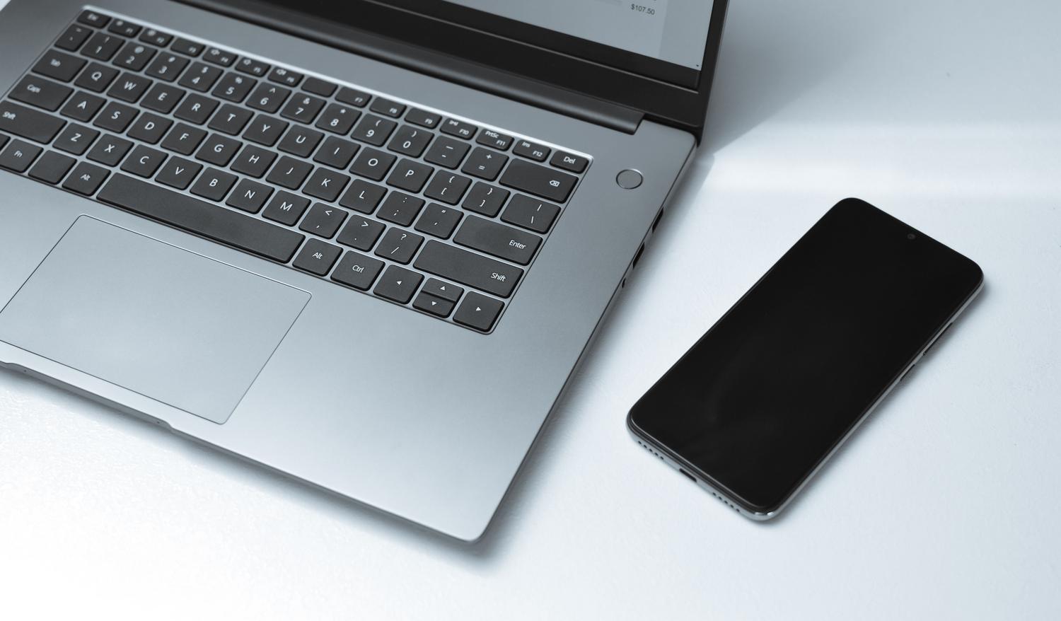 Netbook compacto junto a un smartphone sobre un escritorio, ilustrando una opción económica y ligera para tareas básicas.