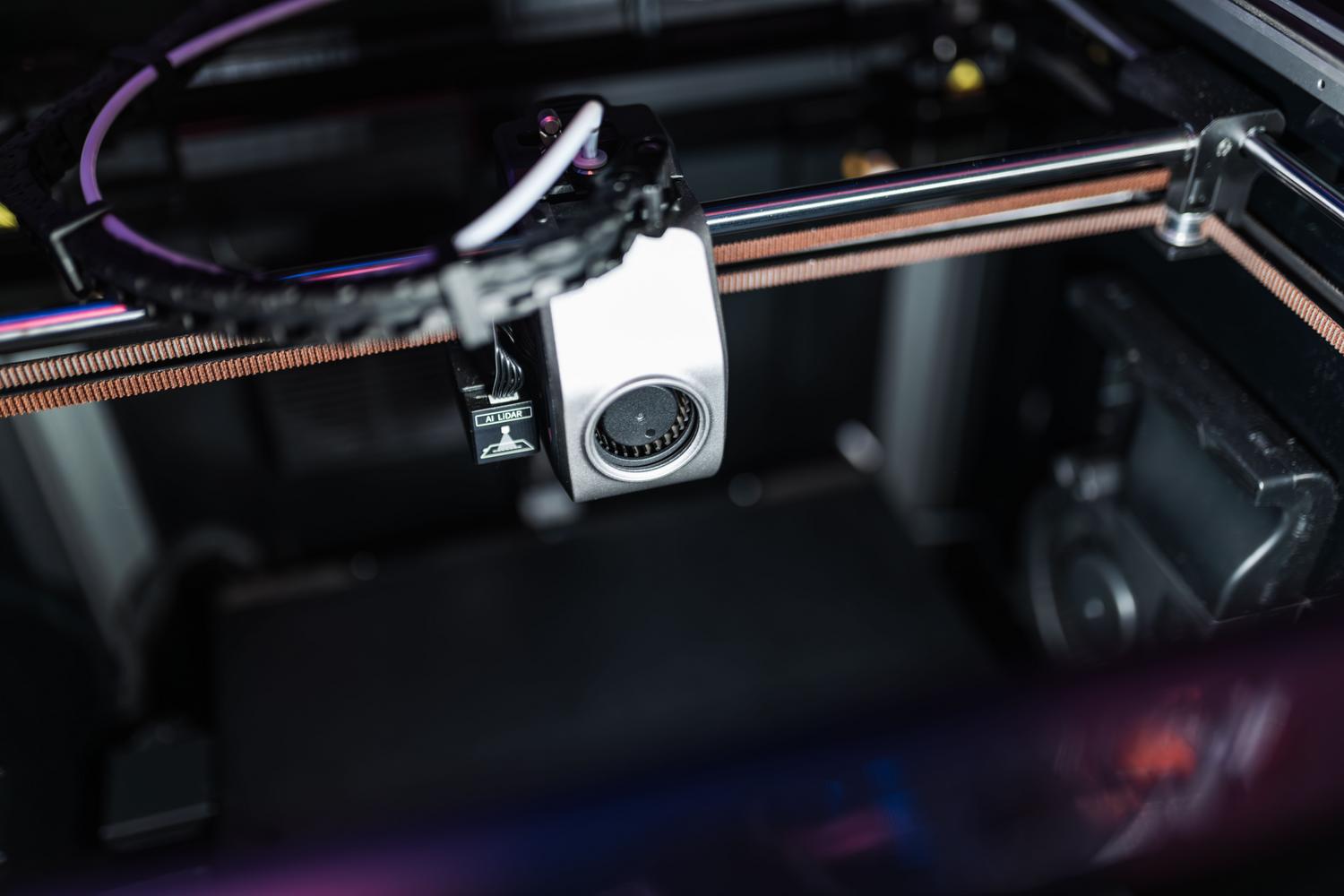 Detalle técnico del cabezal de impresión con rieles lineales y sensores avanzados, representando el hardware de alta performance de las impresoras CoreXY.