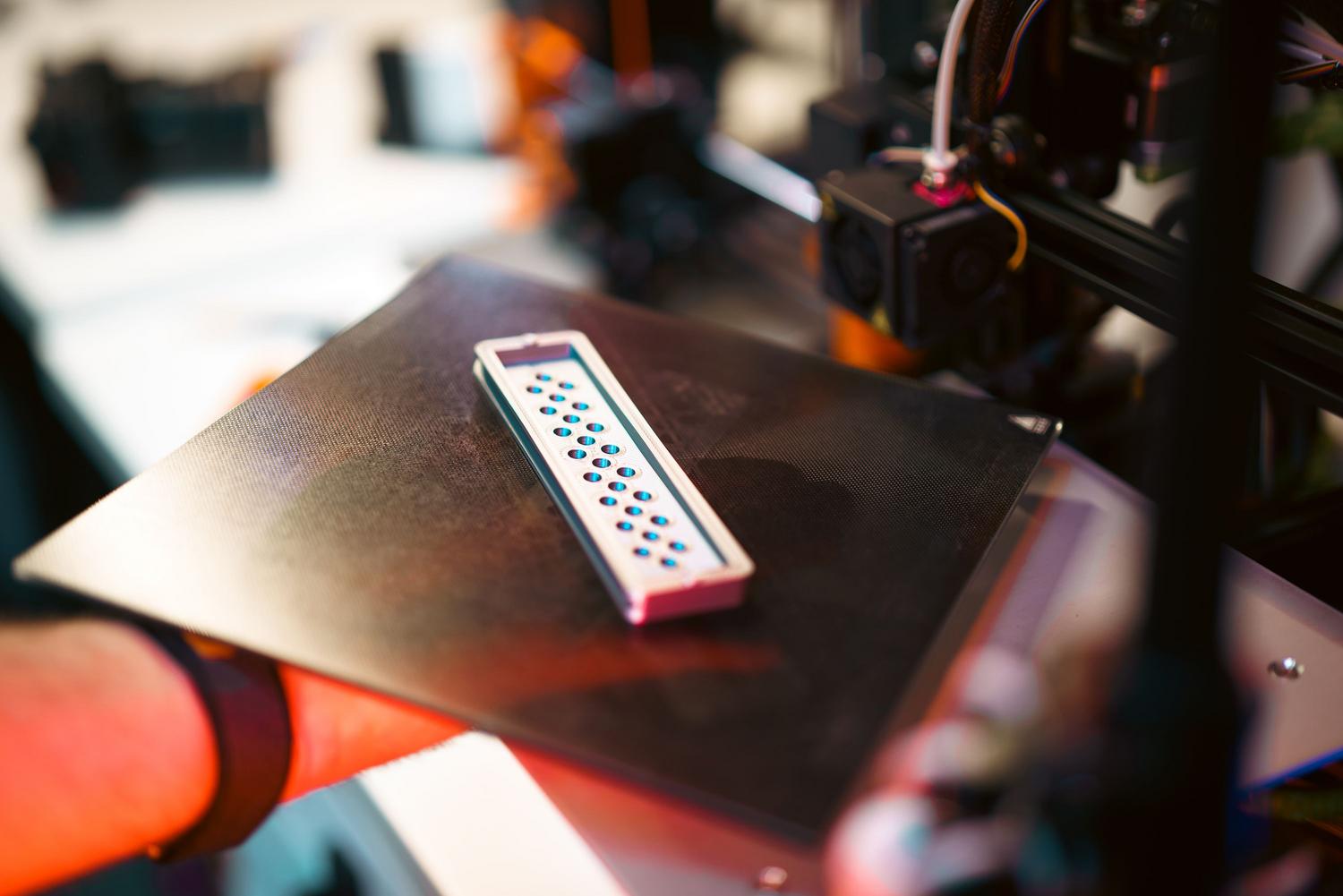 Pieza impresa en 3D sobre una plataforma de una impresora industrial en un taller de ingeniería.