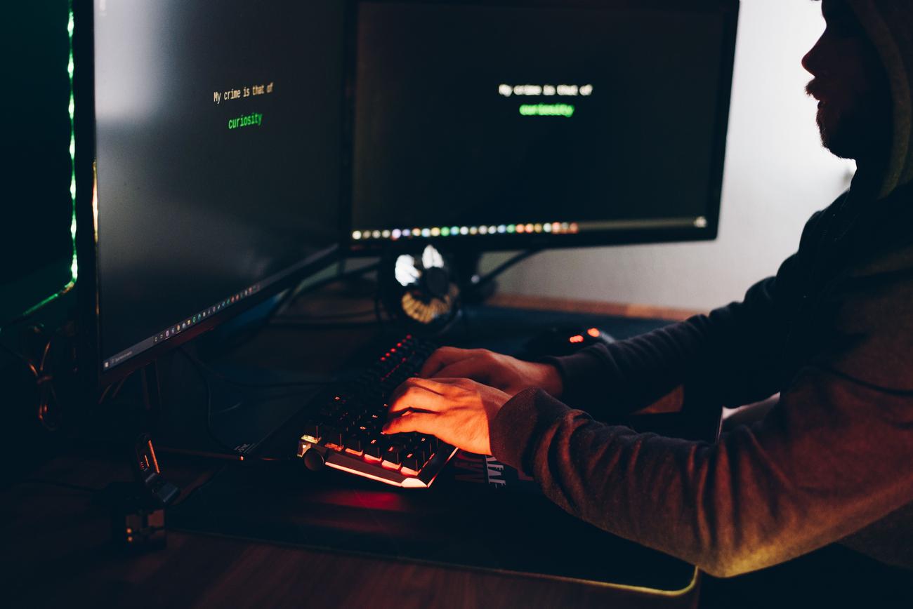 Silueta de um hacker accediendo a pantallas de ordenador, representando el robo de datos personales.