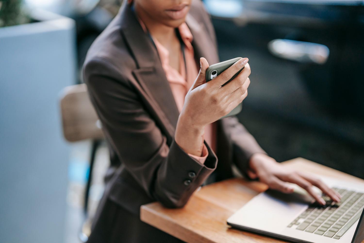Profesional trabajando con un portátil y un smartphone, ideal para ilustrar el uso de WhatsApp Web.