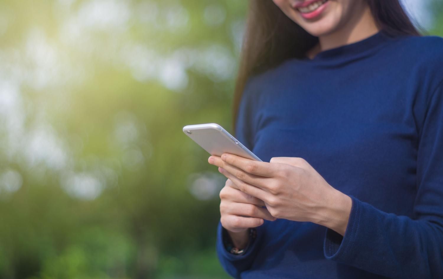 Mujer utilizando su teléfono móvil al aire libre, representando al usuario casual que organiza su día.
