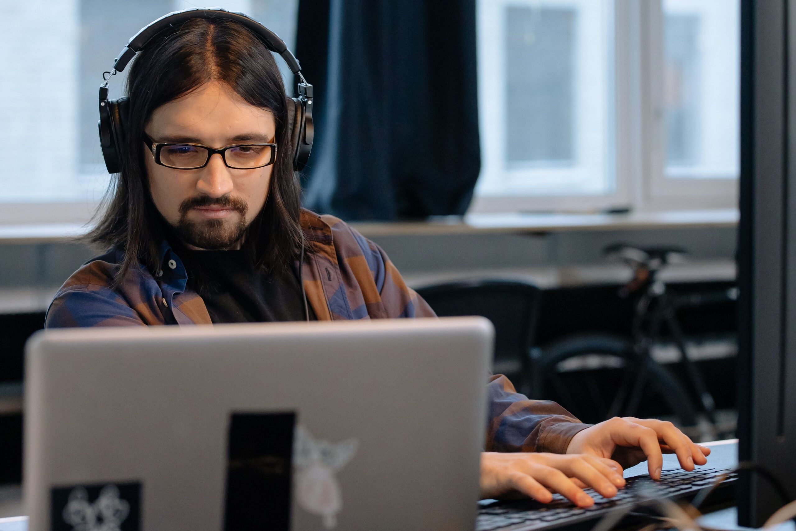 Profesional con auriculares trabajando concentrado en un ordenador, ilustrando el proceso técnico de doblaje y localización sonora de videojuegos.