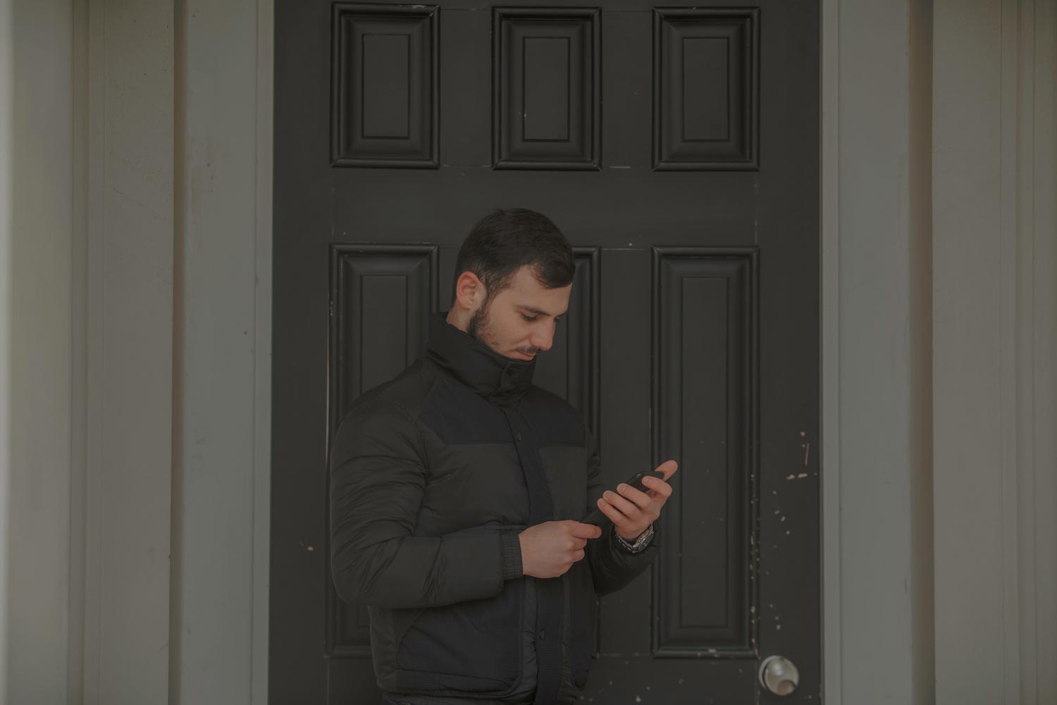 Hombre utilizando su smartphone frente a la puerta de casa para gestionar el acceso remoto