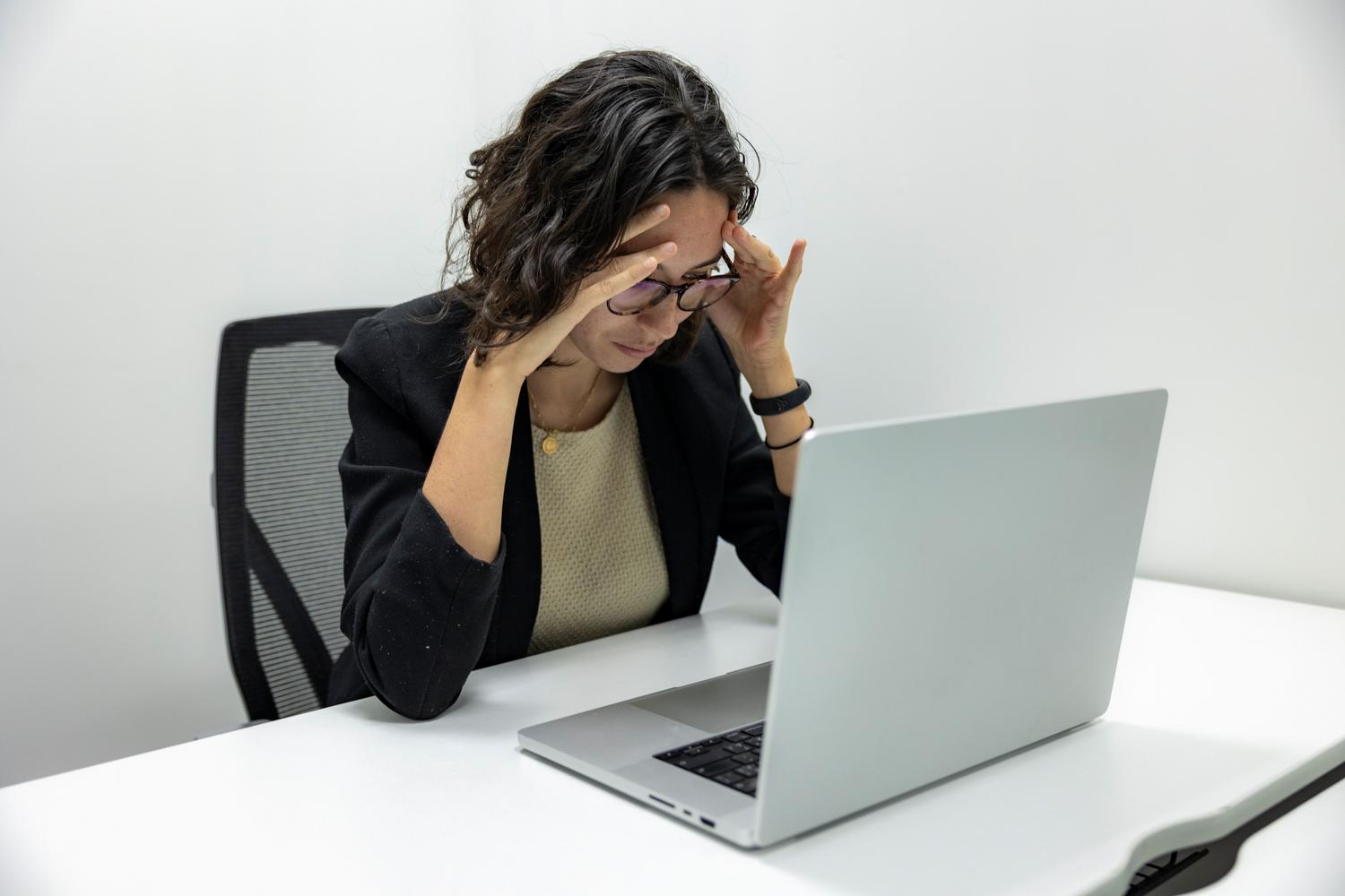Mujer joven estresada frente al ordenador en una oficina, representando la frustración al encontrar errores en Excel.
