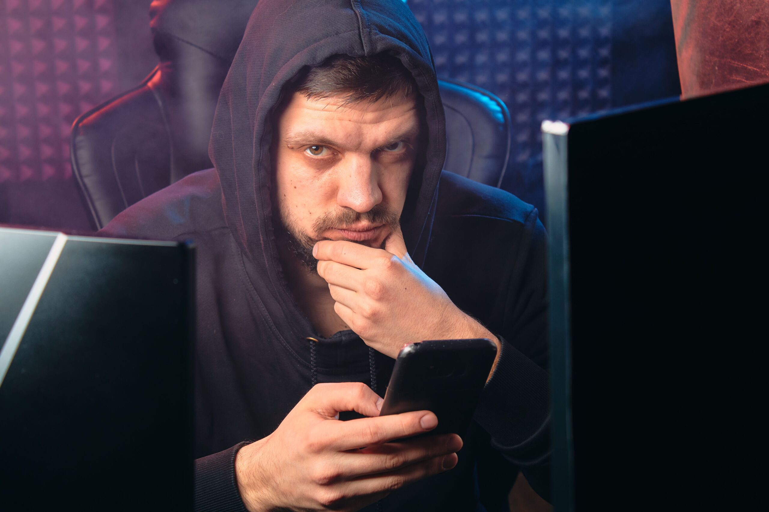 Hacker utilizando um smartphone rodeado de pantallas digitales, ilustrando a vulnerabilidade de Android ante spyware como Arsink.