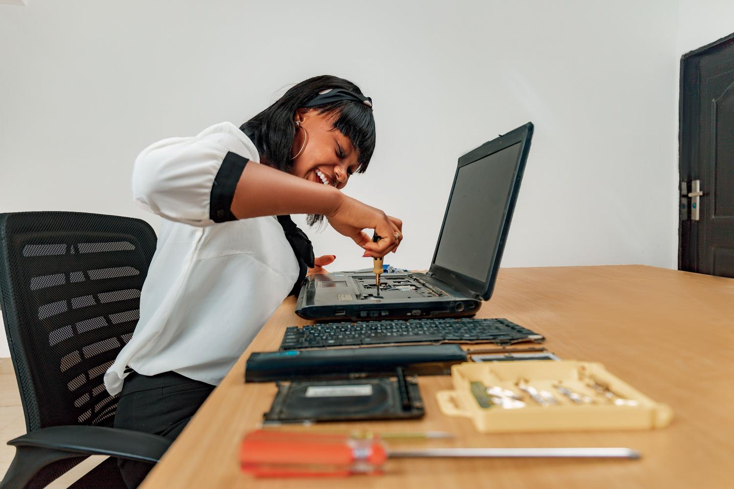 Profissional técnica reparando um computador portátil em um ambiente de trabalho limpo e organizado, transmitindo confiança e rigor.
