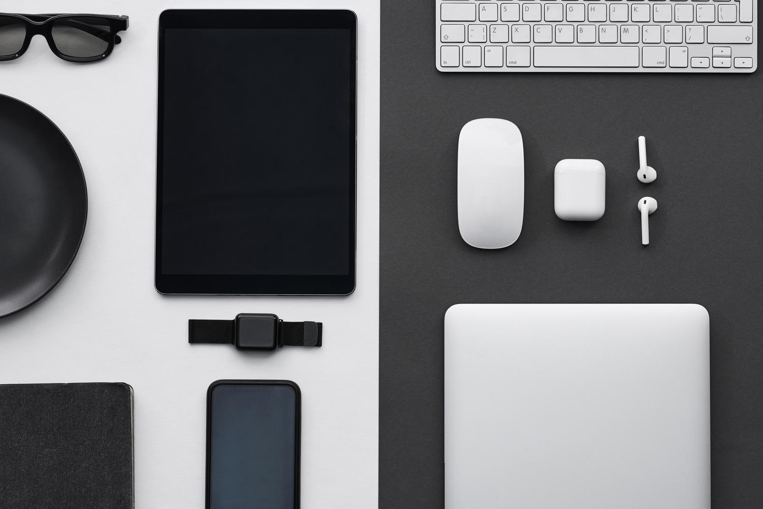 Composição minimalista de gadgets tecnológicos modernos como tabletas, smartphones e relógios inteligentes sobre fundos contrastados.