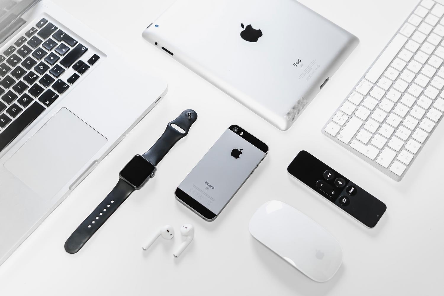 Dispositivos Apple de gama alta, incluindo MacBook, iPad e iPhone, dispostos em um estilo elegante sobre fundo branco.