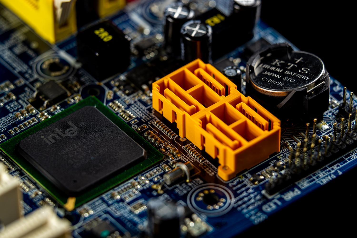 Primer plano de um chip Intel e a bateria CMOS em uma placa base, componentes essenciais para o processo de arranque e configuração do BIOS.