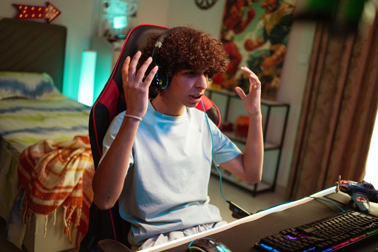 Adolescente concentrado jugando una sesión de videojuegos en línea desde su habitación