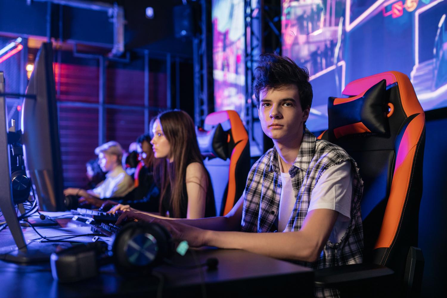 Grupo de adolescentes concentrados en una sesión de juegos competitivos en una arena de esports vibrante