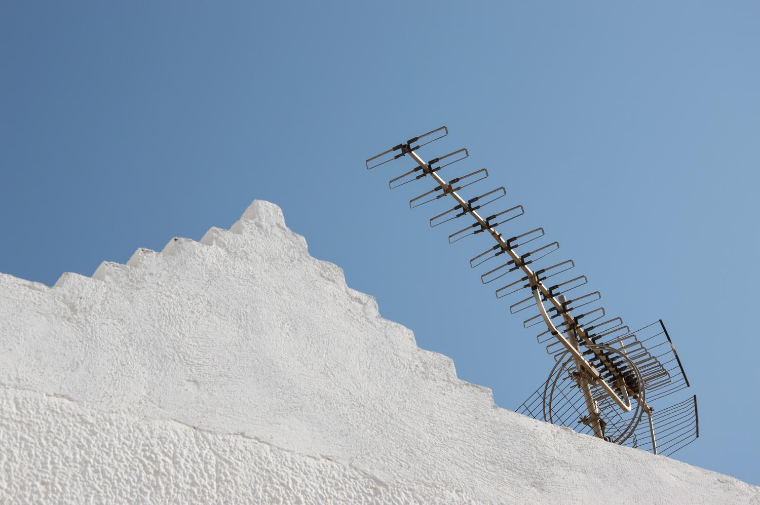 Antena de televisión instalada en el tejado de un edificio bajo un cielo azul despejado, representando la recepción de señal TDT.