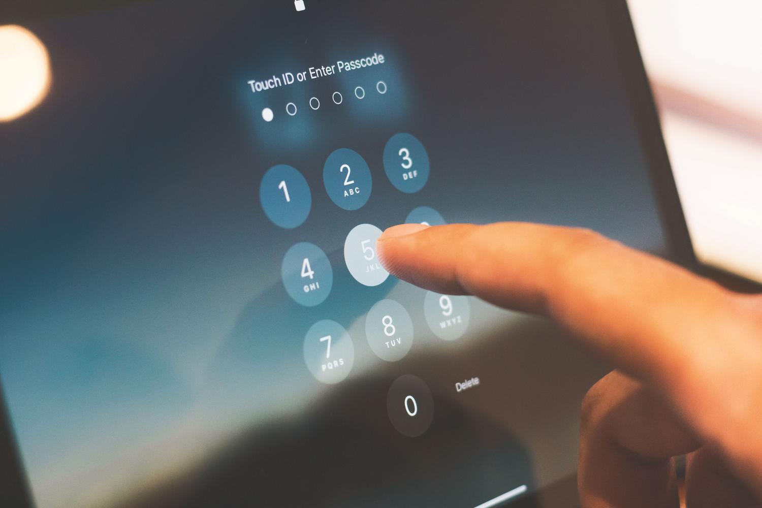 Primer plano de un dedo introduciendo un código de acceso en la pantalla de un smartphone, representando la autenticación.