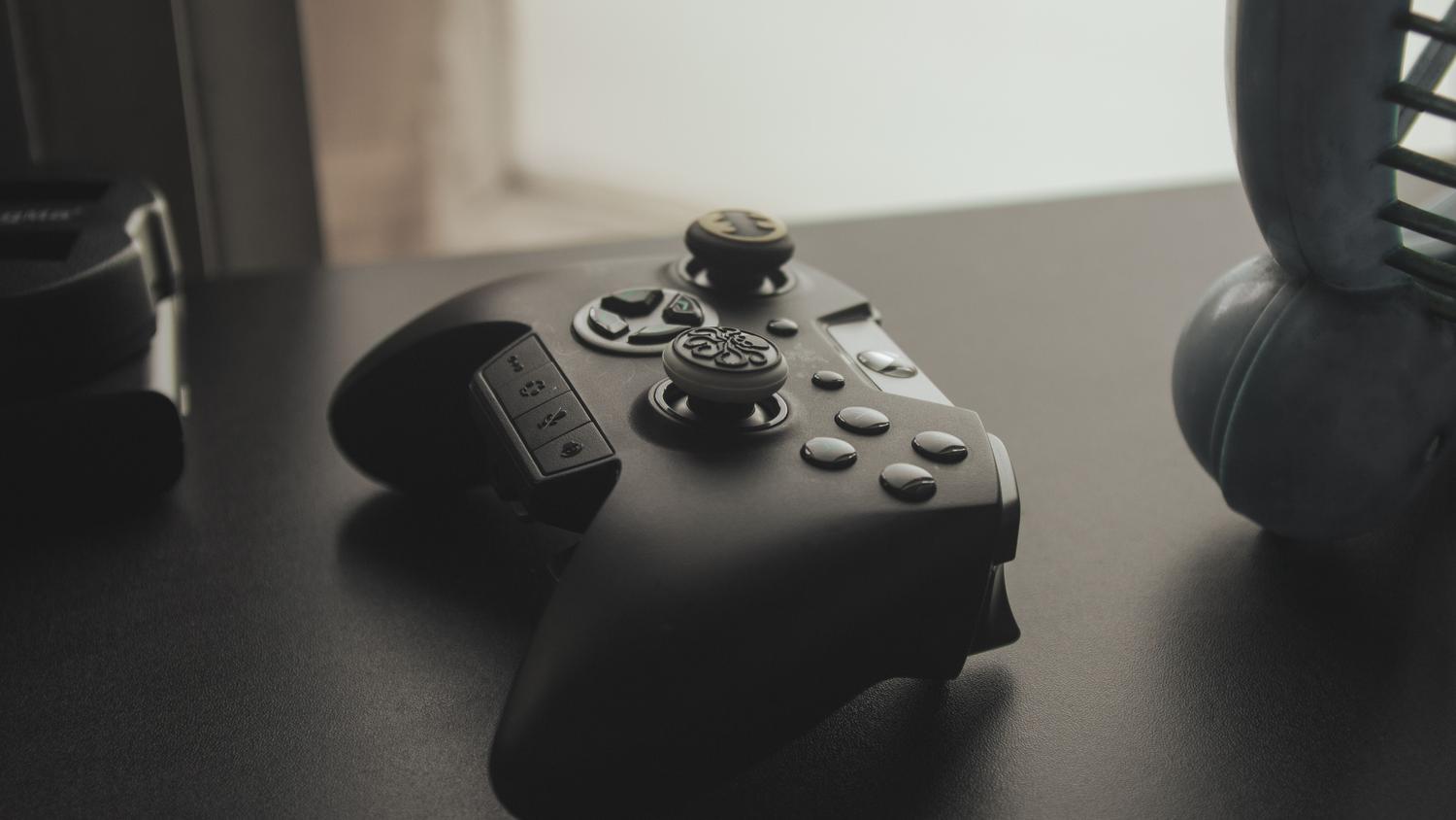 Imagen minimalista de un mando de juegos negro sobre una superficie oscura, útil para secciones de hardware.