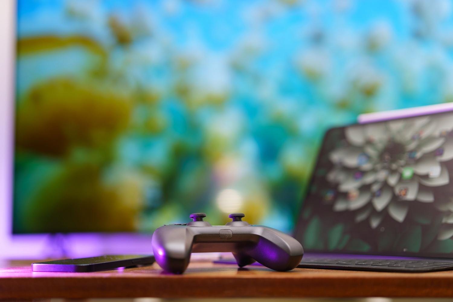 Espacio de juego acogedor con un mando, un portátil y um monitor, ideal para ilustrar la experiencia de juego remoto.