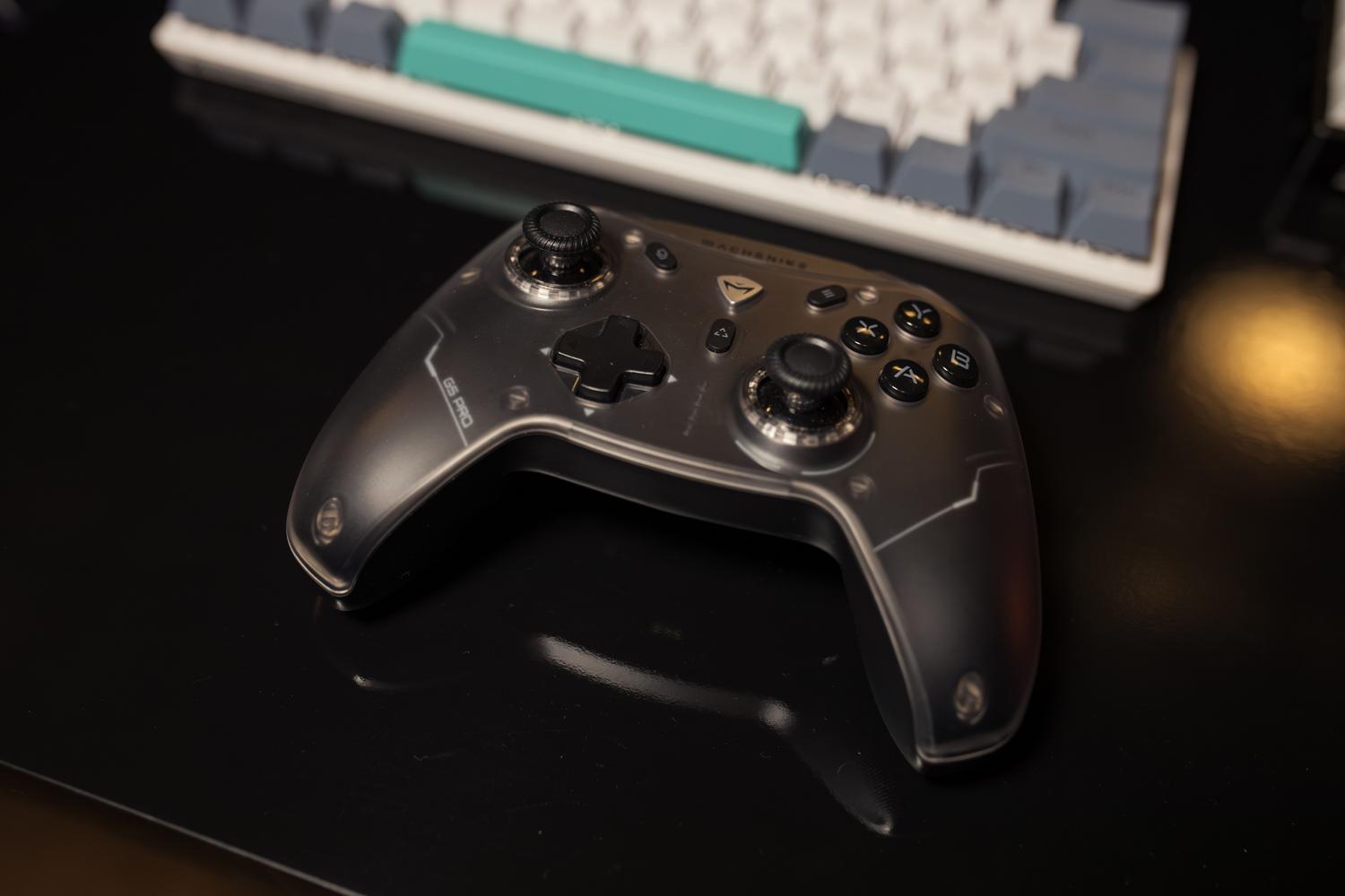 Primer plano de un mando de videojuegos junto a um teclado mecánico en un escritorio moderno.