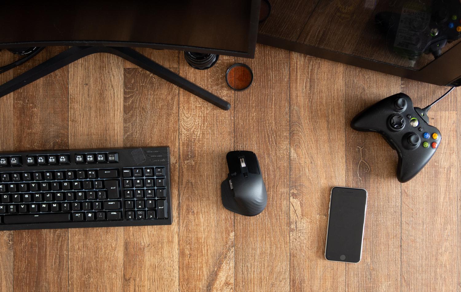 Vista superior de un mando de juego, teclado y ratón sobre un escritorio de madera, representando un entorno de juego en PC.