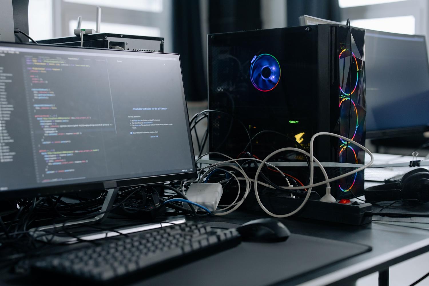 Setup de computadora de escritorio con monitor, torre RGB y regleta de corriente, ilustrando el consumo eléctrico general.