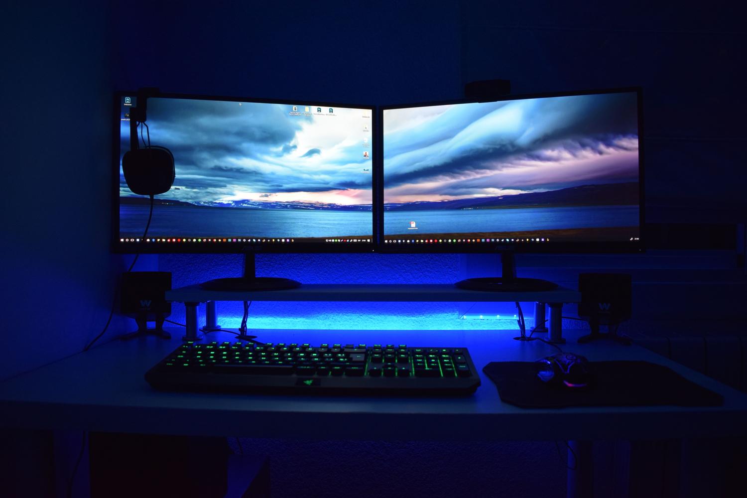 Setup gaming com doble monitor y periféricos RGB, mostrando cómo los accesorios adicionales aumentan el gasto de luz.