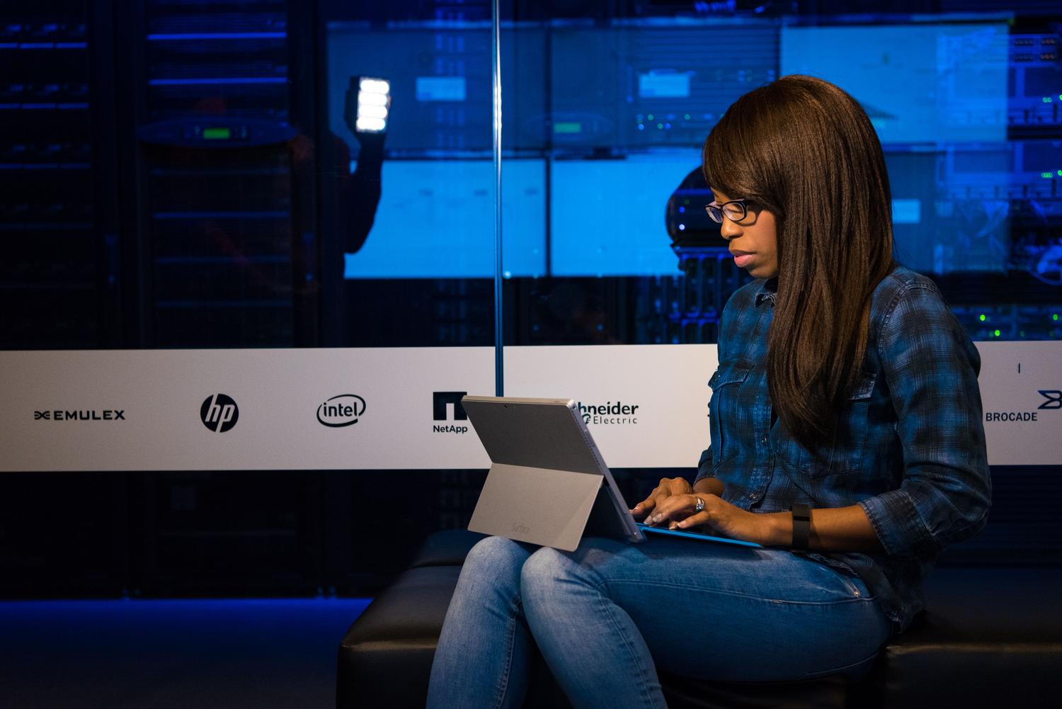 Persona trabajando con una laptop en una sala de servidores, representando la gestión de datos y la colaboración.