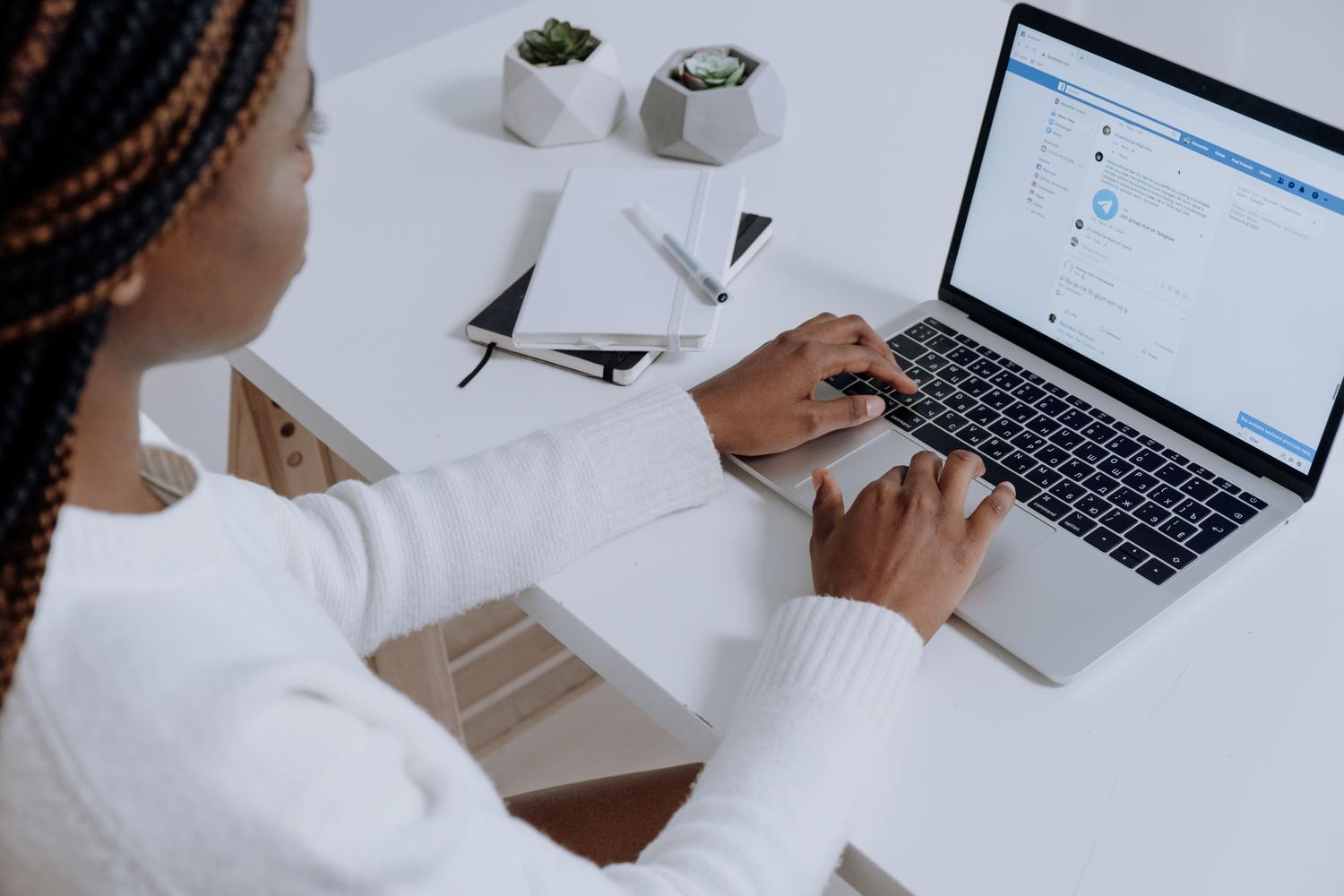 Content creator managing social media on a laptop in a bright, modern workspace.