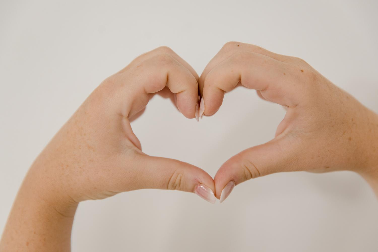Primer plano de manos formando un corazón, ilustrando el gesto de corazones en videollamadas de WhatsApp.