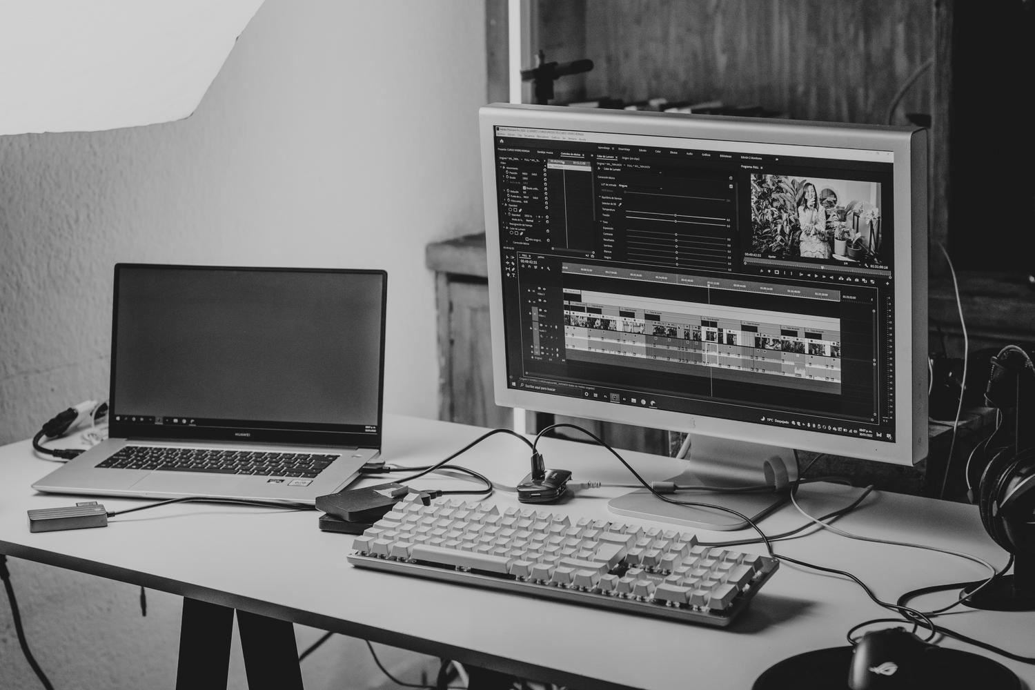 Espacio de trabajo minimalista con portátil y monitor para edición de contenidos digitales.