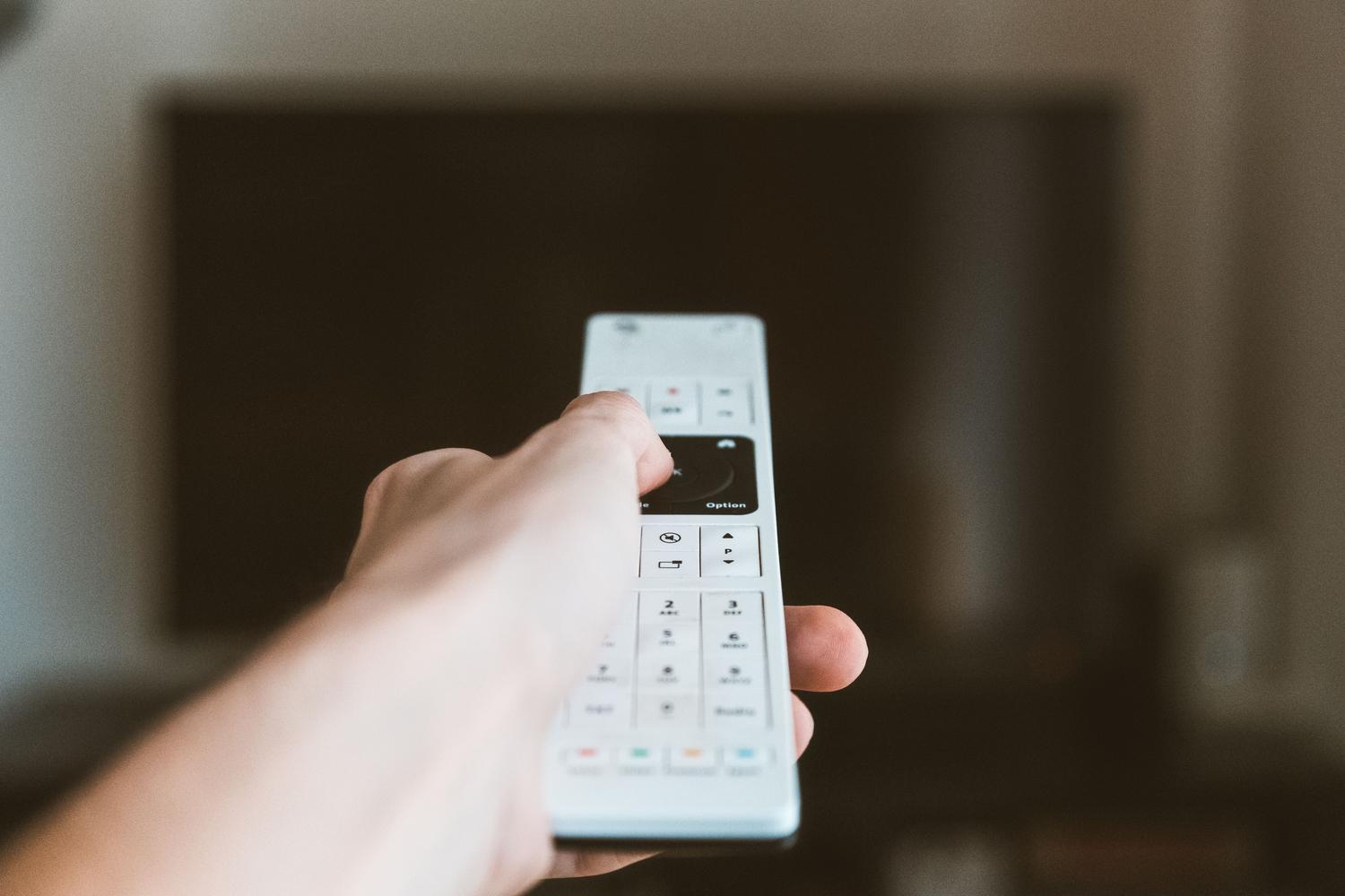 Primer plano de una mano utilizando el mando a distancia para acceder a las opciones de desarrollador de una televisión.