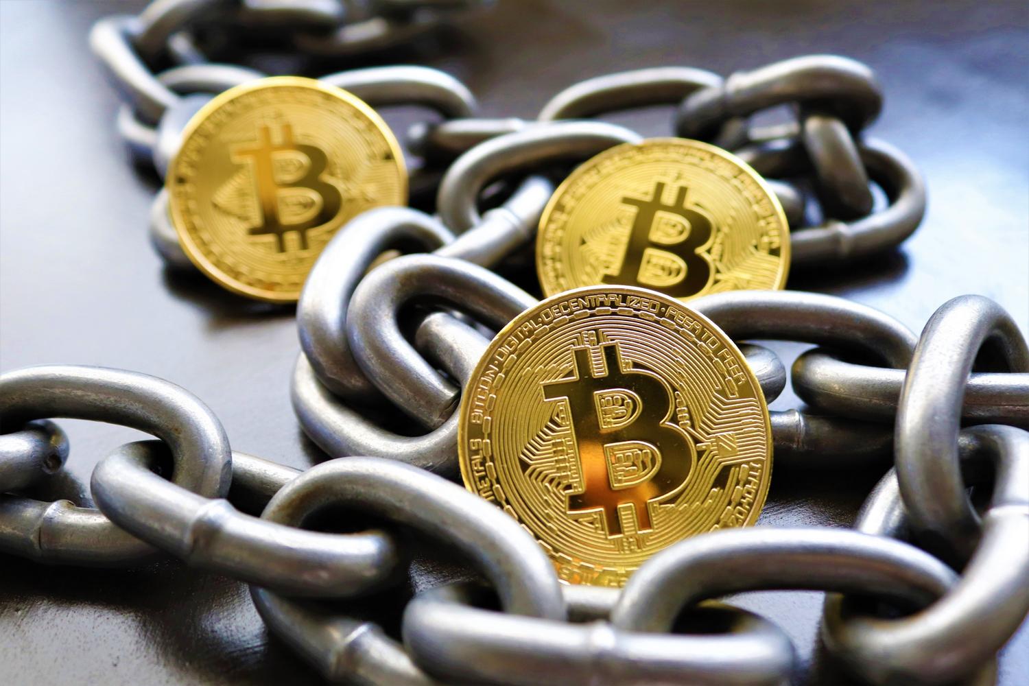 Monedas de Bitcoin entrelazadas con cadenas metálicas, una metáfora visual de la seguridad, el valor y la inmutabilidad de los activos digitales.