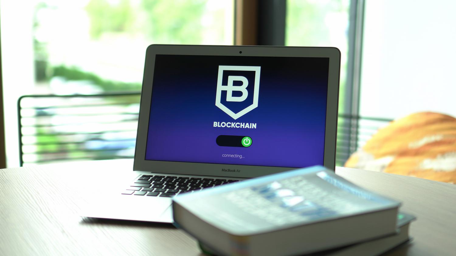 Laptop mostrando una interfaz de conexión blockchain en un entorno moderno, representando la gestión y propiedad de activos digitales.