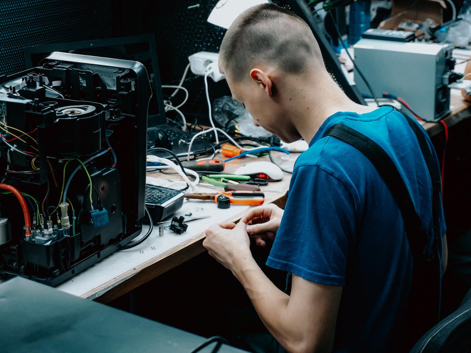 Técnico especializado trabajando en la reparación de dispositivos electrónicos en un taller.