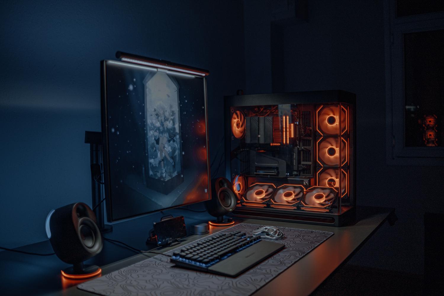 Setup de PC gaming de alta gama en una habitación con luz tenue, destacando la iluminación RGB y el monitor panorâmico.