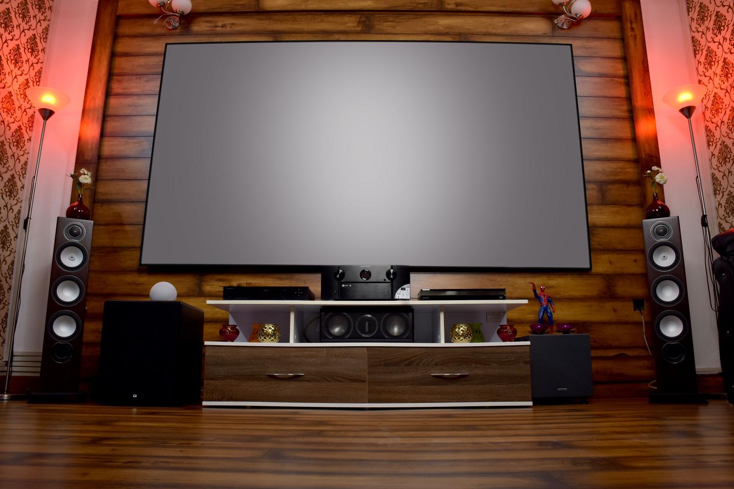 Lujosa sala de cine en casa con sistema de sonido envolvente y un subwoofer prominente en la esquina frontal izquierda.