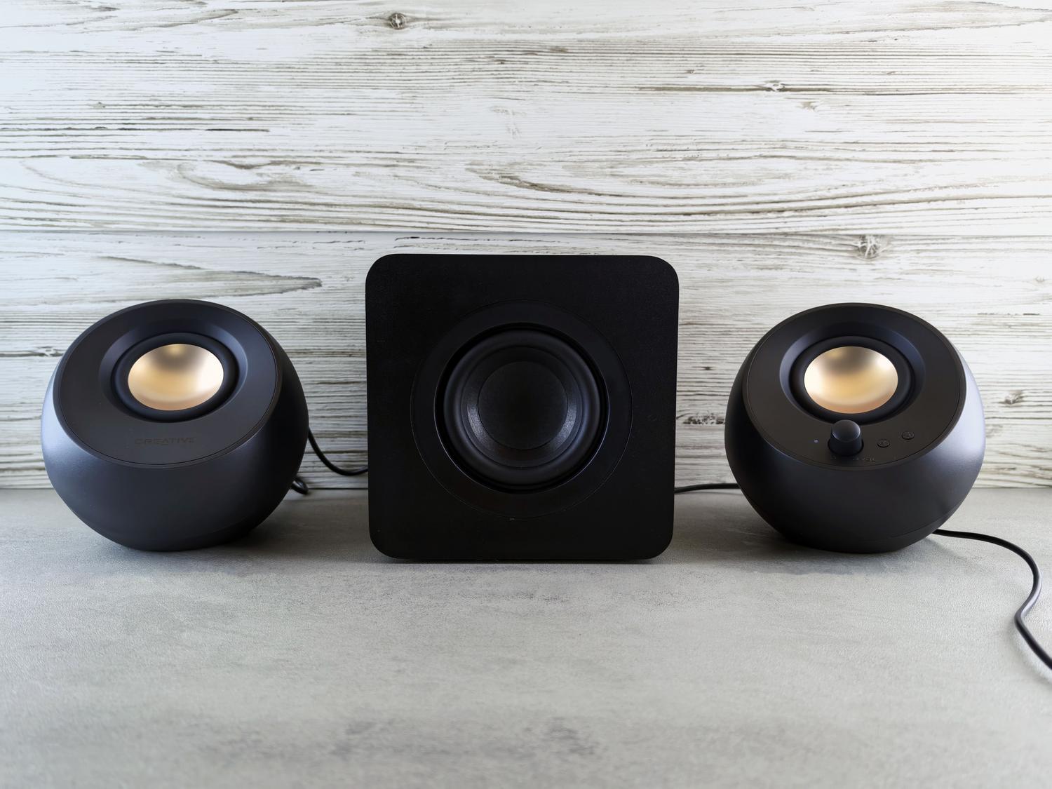 Sistema de altavoces 2.1 con subwoofer central y satélites sobre un fondo neutro.