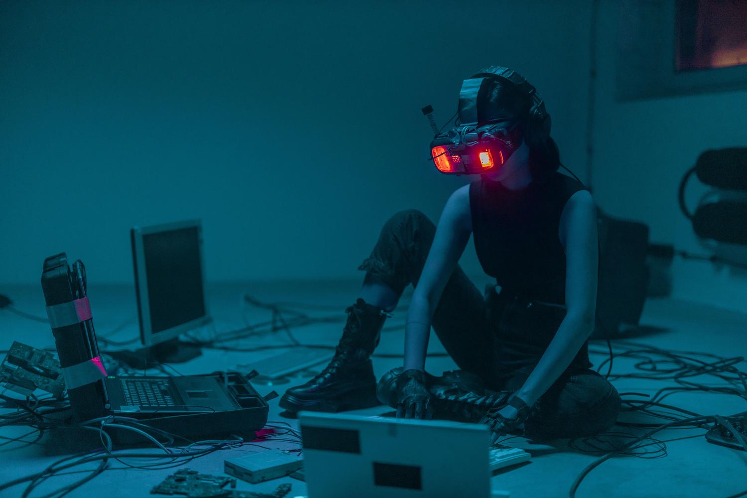 Persona con visor de realidad virtual en un entorno lleno de cables y luces neón, representando amenazas digitales avanzadas y hacking futurista.