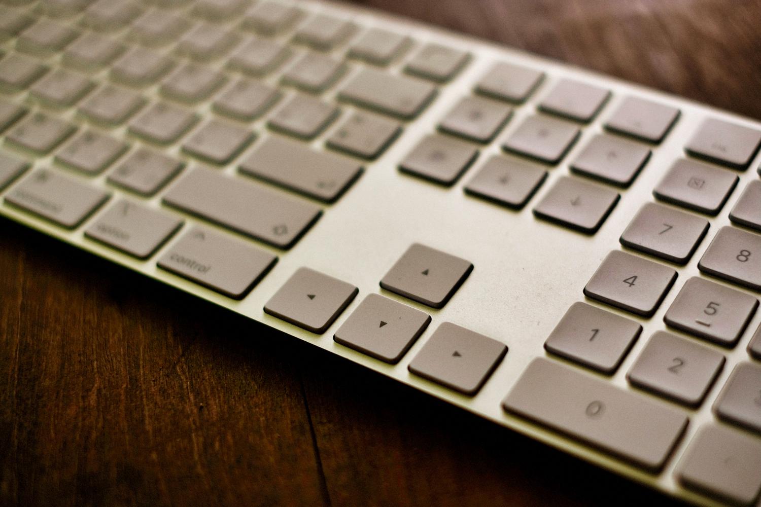 Teclado de computadora moderno y elegante sobre un escritorio de madera, proporcionando un contexto profesional de trabajo digital y escritura.