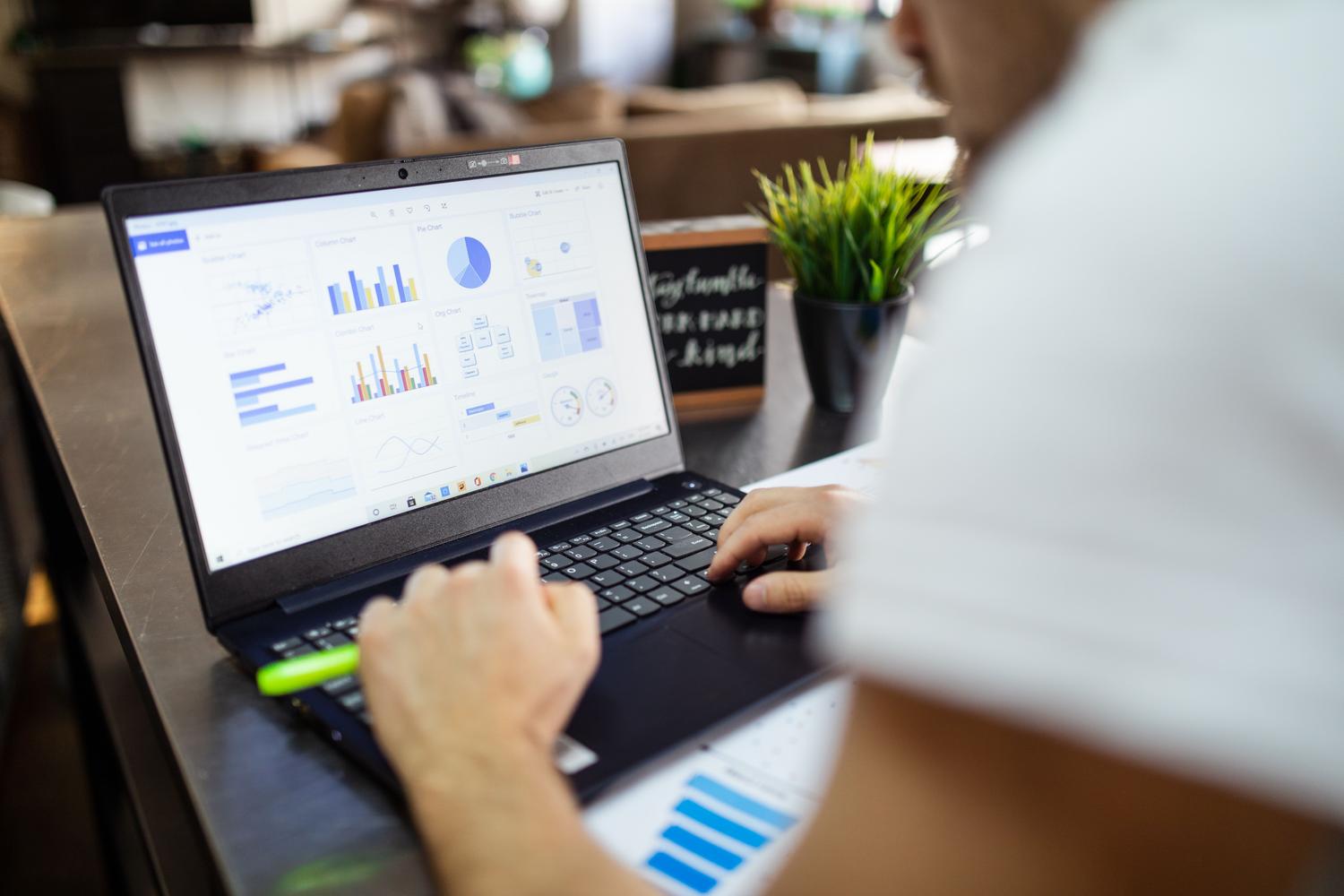 Análise de dados empresariais com gráficos e tabelas na tela de um notebook.