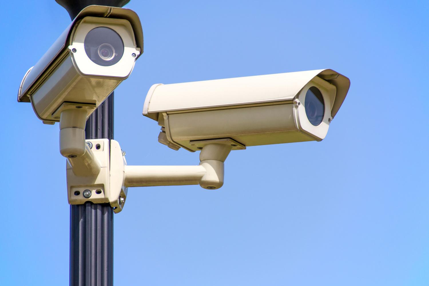Cámaras de seguridad tipo bala instaladas en un poste exterior bajo un cielo azul para vigilancia perimetral.