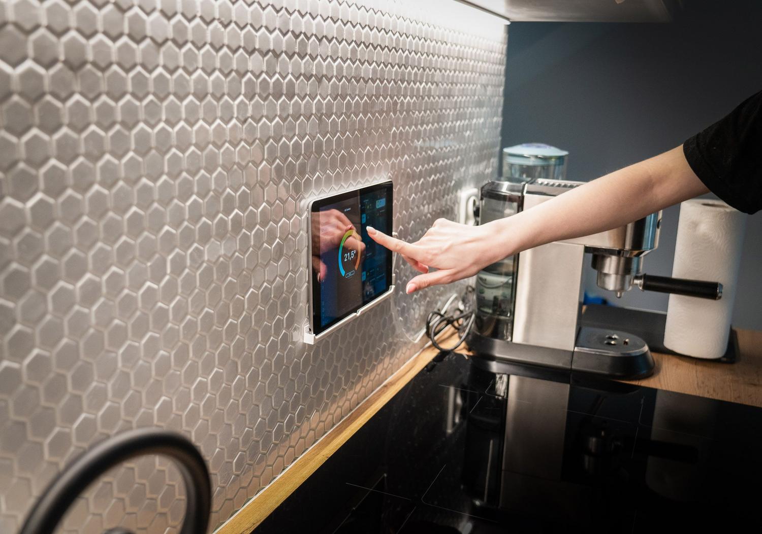 Panel de control táctil de domótica integrado en la pared de una cocina moderna para la gestión centralizada del hogar.