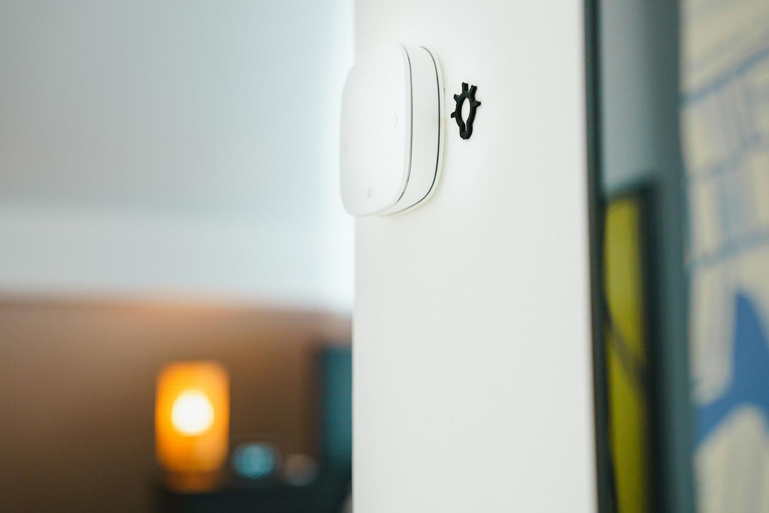 Primer plano de un interruptor de luz inteligente minimalista instalado en una pared blanca.