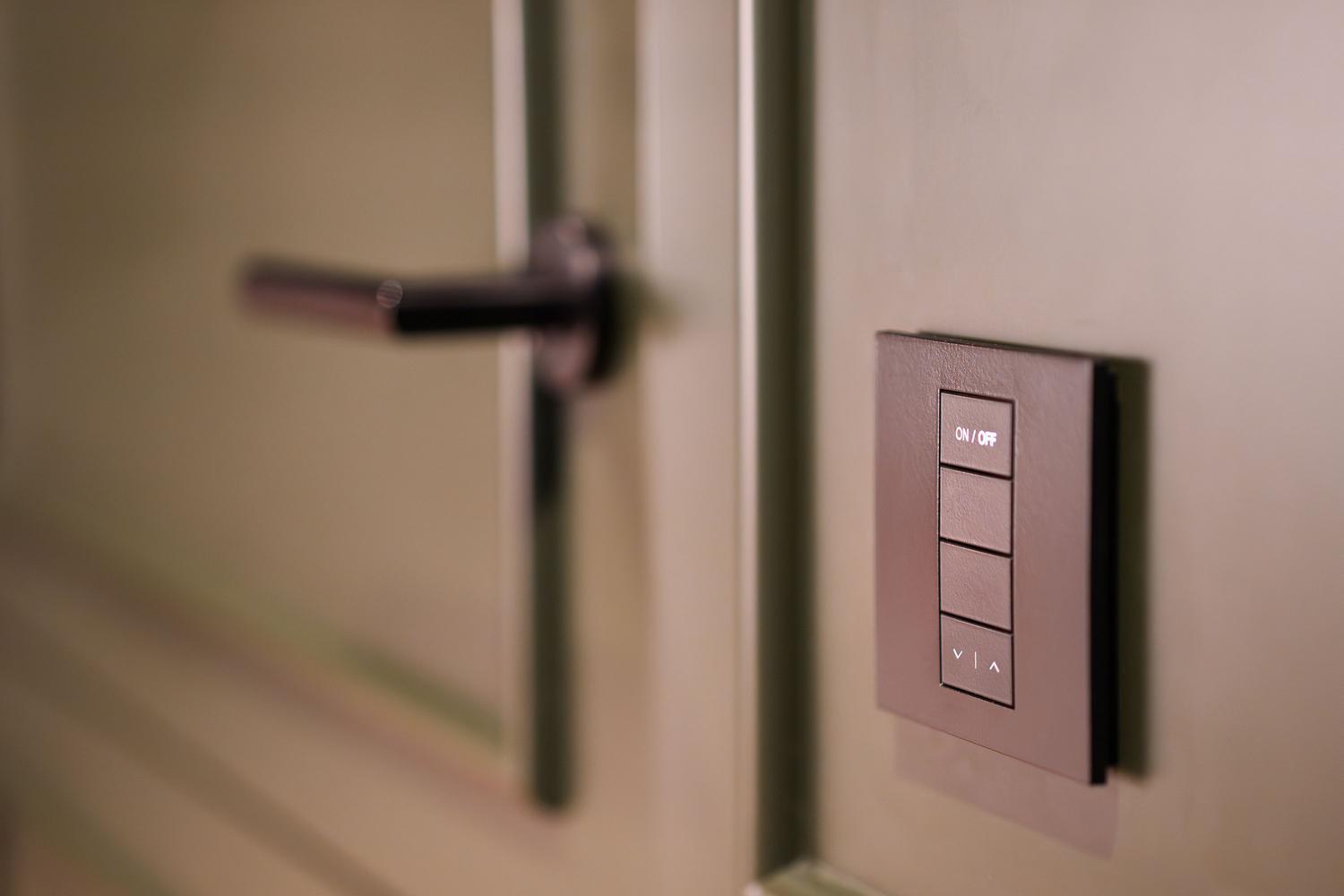 Panel de control domótico junto a la manija de una puerta moderna, ilustrando el control de accesos y automatización.